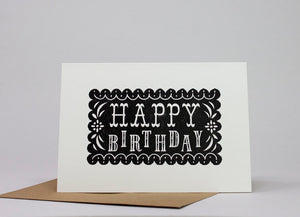 Lino printed greetings cad. Black background with white Happy Birthday letters