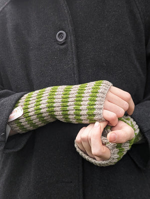 A person wearing green and grey striped knitted fingerless gloves.