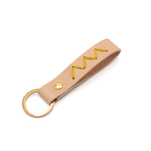 Pale pink leather keyring with zig-zag yellow stitch. White background.