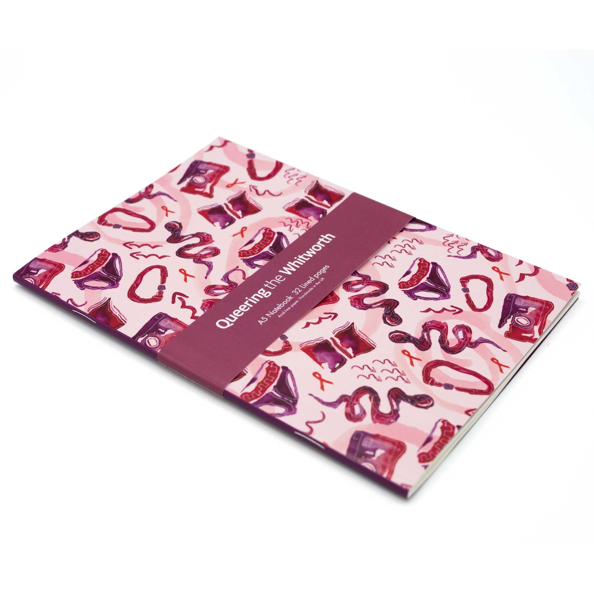 Notebook with print by Sarah-Joy Ford againt a white background. Pink, red and purple pattern design. 