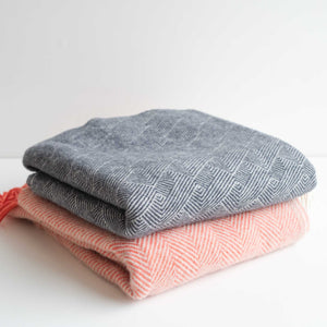 A grey blanket folded on top of a red blanket - white background