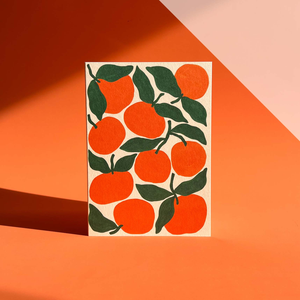 Card with tangerine illustration pattern photographed against orange backdrop