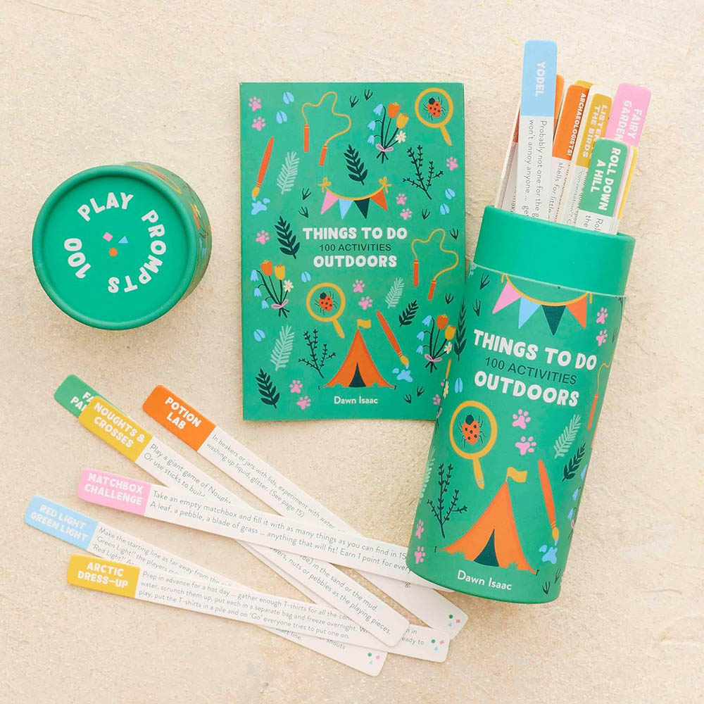 A green tube filled with colorful cards sits next to a book titled "Things To Do Outdoors - 100 Activities." The cards have text and pictures showing ideas for outdoor activities for kids. 