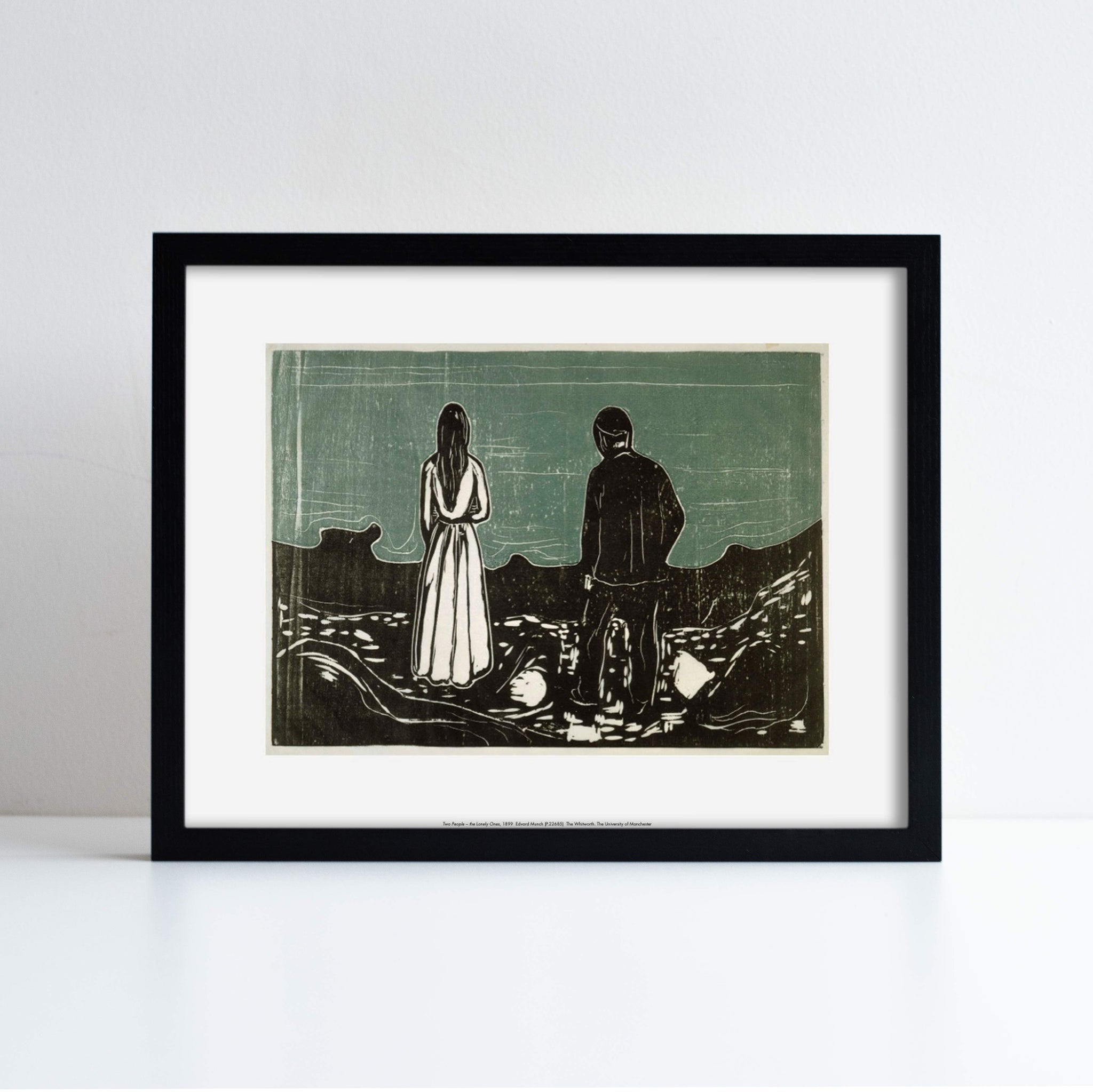 Reproduction of Edvard Munch's Two People The Lonely Ones, photographed in a black frame against a white background
