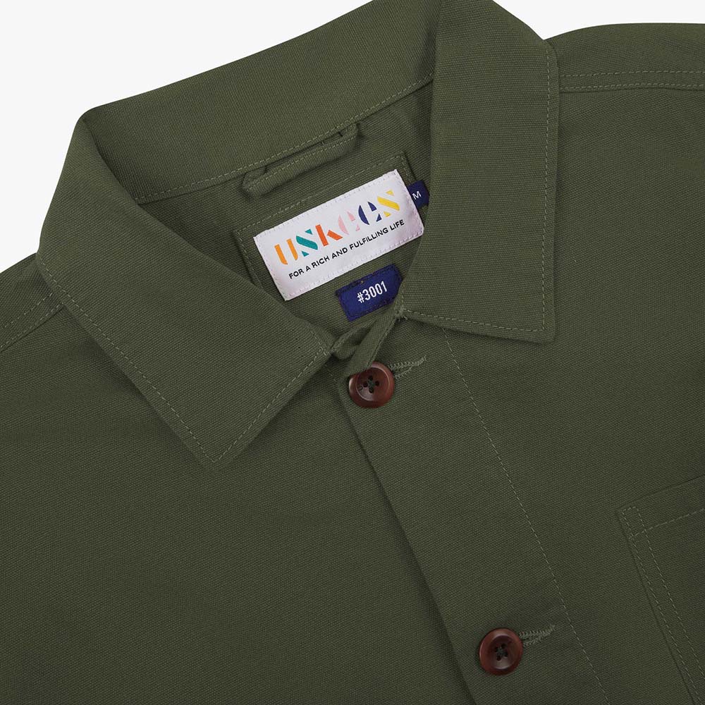 Green shirt with a brand label on the collar against a white background