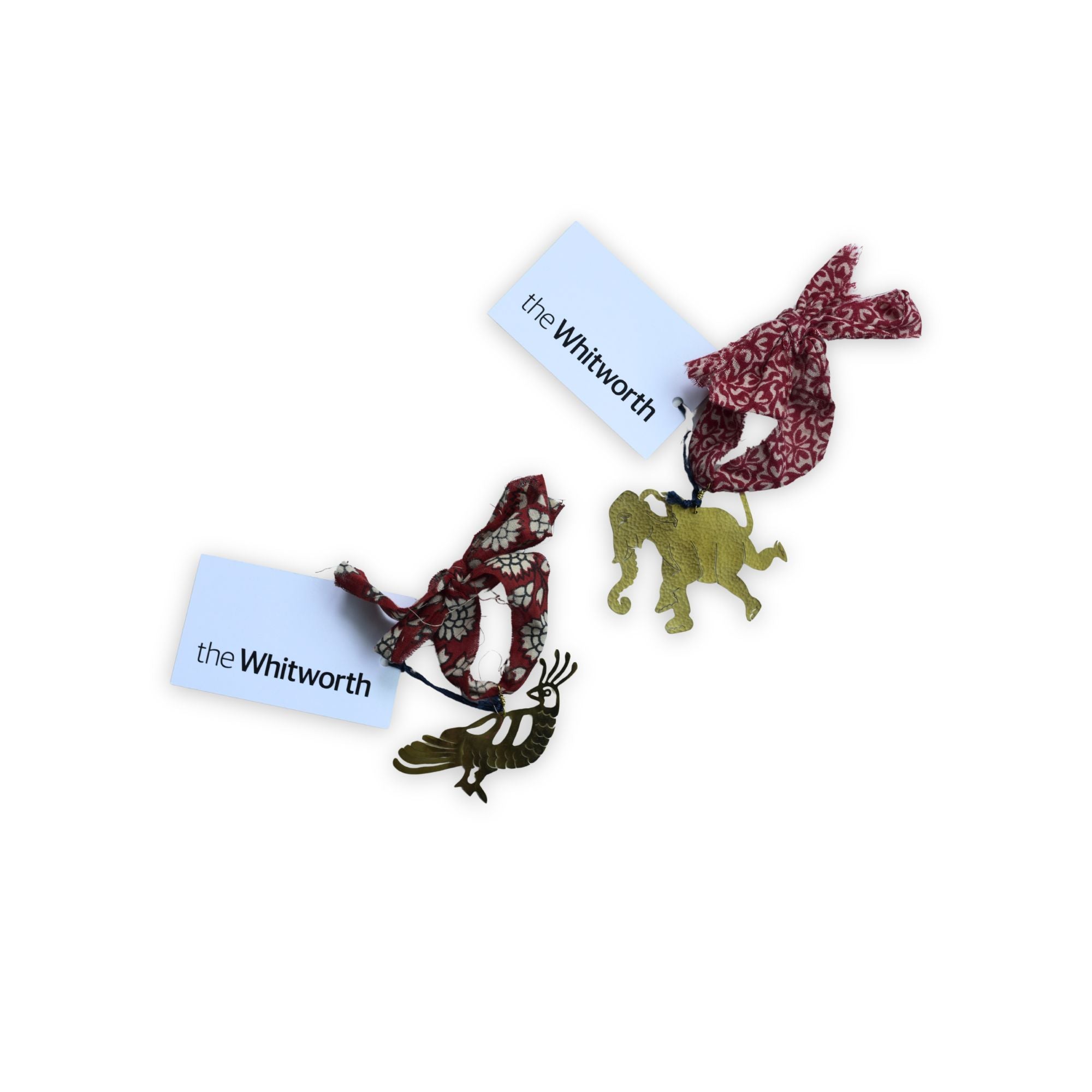 two brass decorations with fabric ribbons and white card ags with blakc text 'the Whitworth'