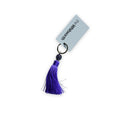 Purple tassel keyring on a white surface with a swing tag attached.