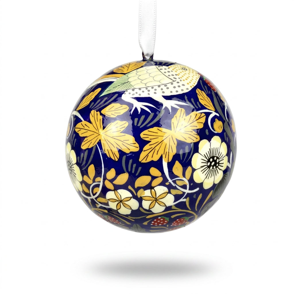 A spherical decorative bauble with a glossy navy blue background, decorated with large yellow and white flowers, green leaves, and a white bird motif, hanging from a white ribbon against a white background.