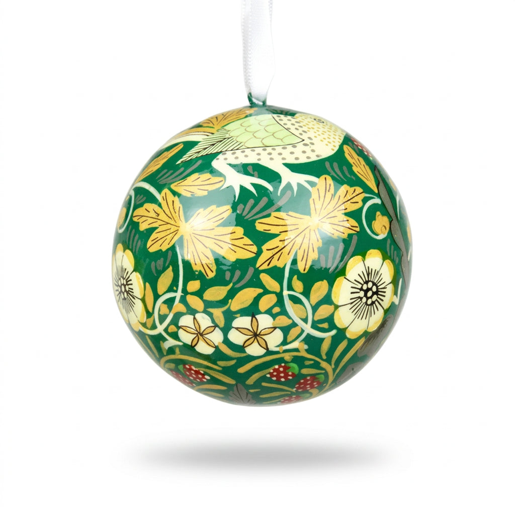 A spherical decorative bauble with a glossy green background, decorated with yellow flowers, white leaves, and a bird motif, hanging from a white ribbon against a white background.