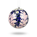 A spherical Christmas bauble featuring a William Morris-style floral pattern with white and light pink leaves on a dark navy blue background, suspended by a white string.