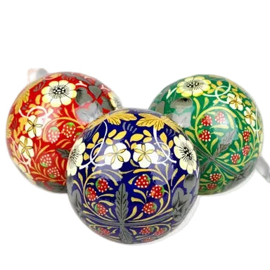 Three hand-painted Christmas baubles with intricate floral and berry patterns in red, blue, and green, arranged on a white background.