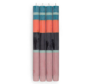 Set of four striped candles with pink, orange, and blue bands on a white background