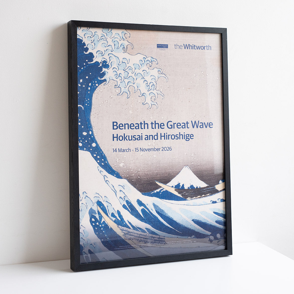 Framed poster for 'Beneath the Great Wave' exhibition at the Whitworth with wave design and text.