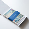 Open set of greetings cards - top card is presented which features a Japanese Woodblock design. Branded navy Whitworth belly band. Presented on a light grey background.