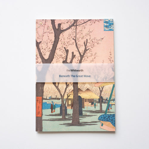 Notebook cover with cherry blossom trees and a scene of people by a river, featuring 'the Whitworth' branding.