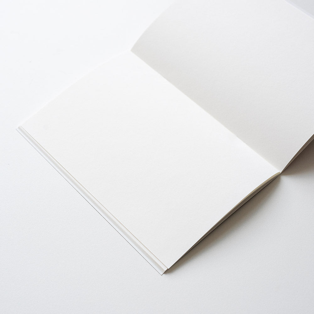 Plain notebook with pages open, against light grey background