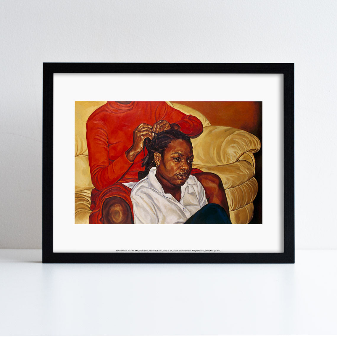 An artwork by Barbara Walker of a young girl sat in front of another person who is sat on a couch. Someone is doing her hair. Print framed in a black frame.