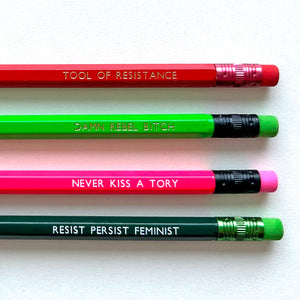 Four colourful pencils with feminist slogans are arranged diagonally on a light background.