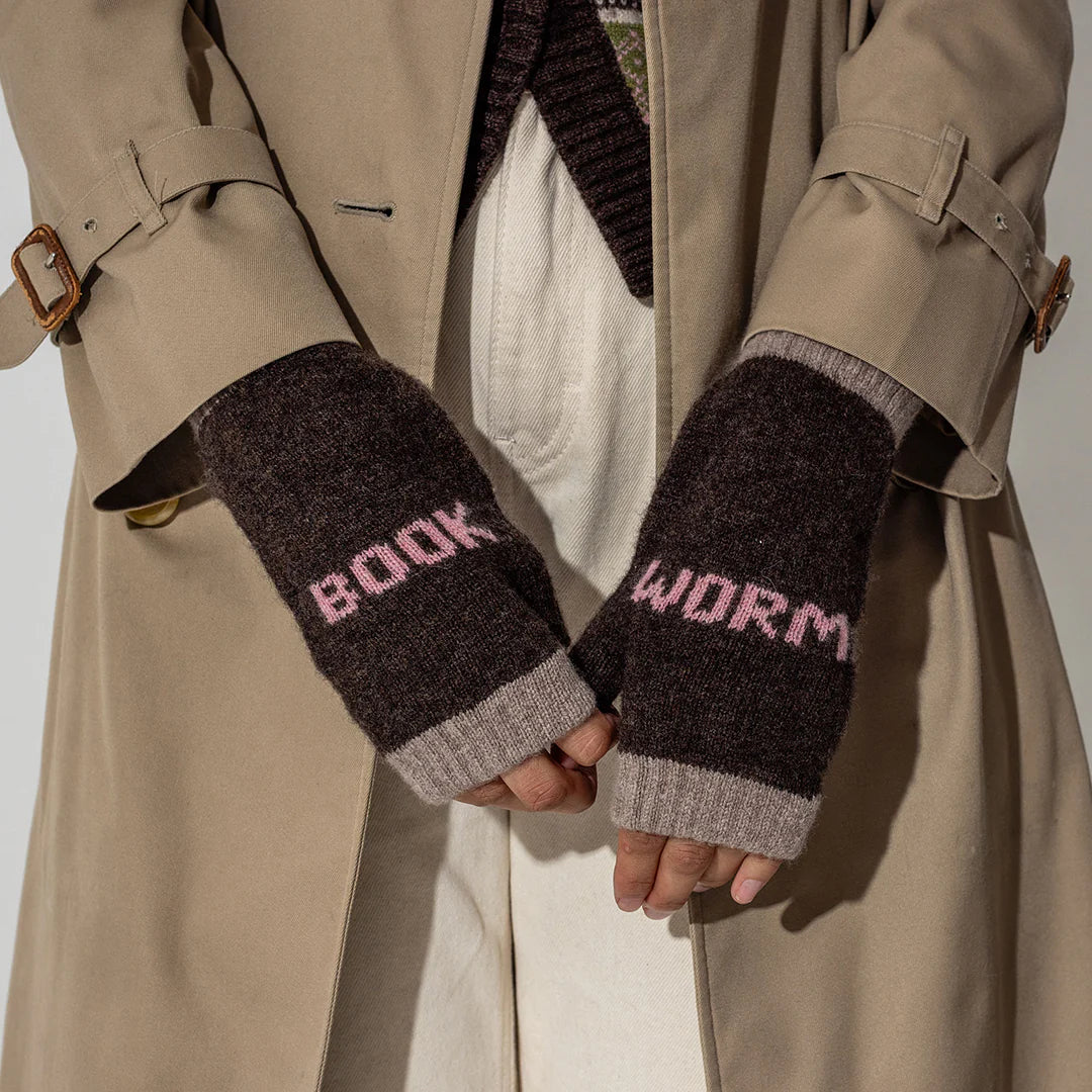 Person in beige trench coat wearing brown and beige mittens with 'book' on the left and 'worm' on the right.