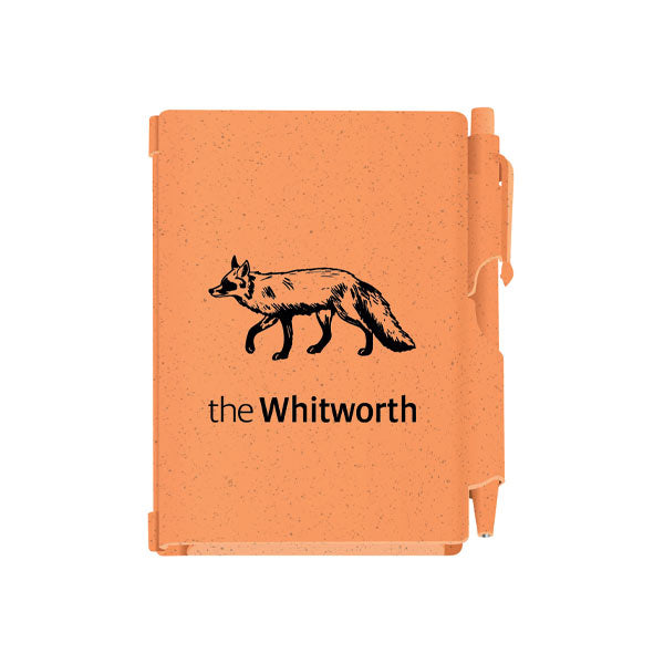 Orange notebook and pen against white background. Notebook has an illustration of a fox and the Whitworth logo.
