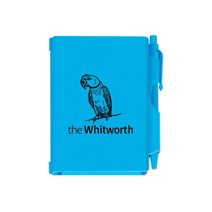 Blue notebook and pen against white background. Notebook has an illustration of a parakeet and the Whitworth logo.