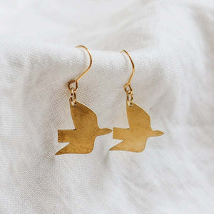 Brass hook earrings in the shape of a dove against a. white background.