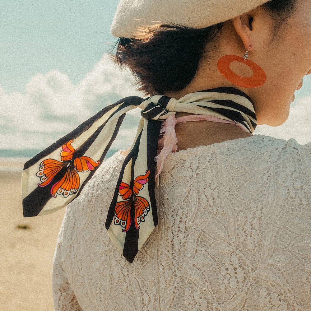 Person wearing a scarf with butterfly design on a beach