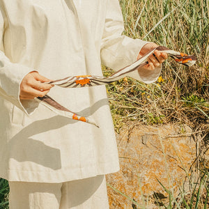 Person holding the scarf with orange and white design in a natural setting