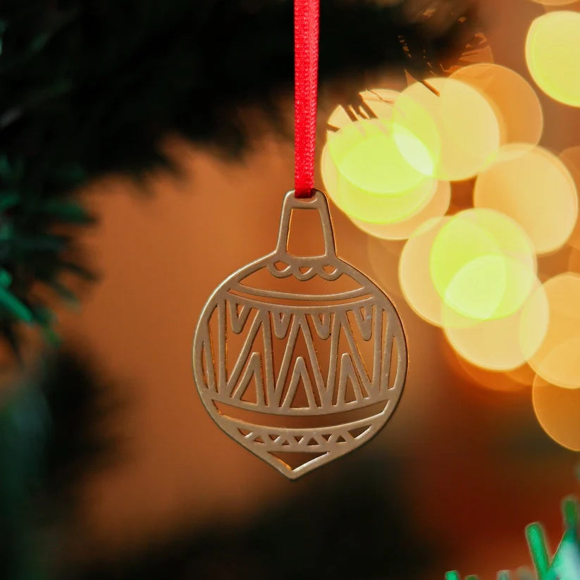 Close up photograph of a brass decoration in the shape of a bauble, on a Christmas tree with some lights in the background.