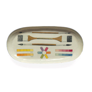An oval-shaped enamel tray featuring a colour chart with various shades of red, orange, yellow, green, blue, and purple. The names of each colour are printed below the corresponding swatch.