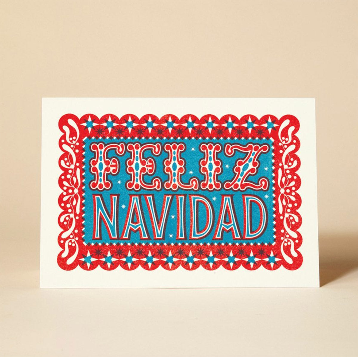 A vibrant Christmas card featuring the phrase "FELIZ NAVIDAD" in red and blue lettering, surrounded by intricate paper cut-out designs. 