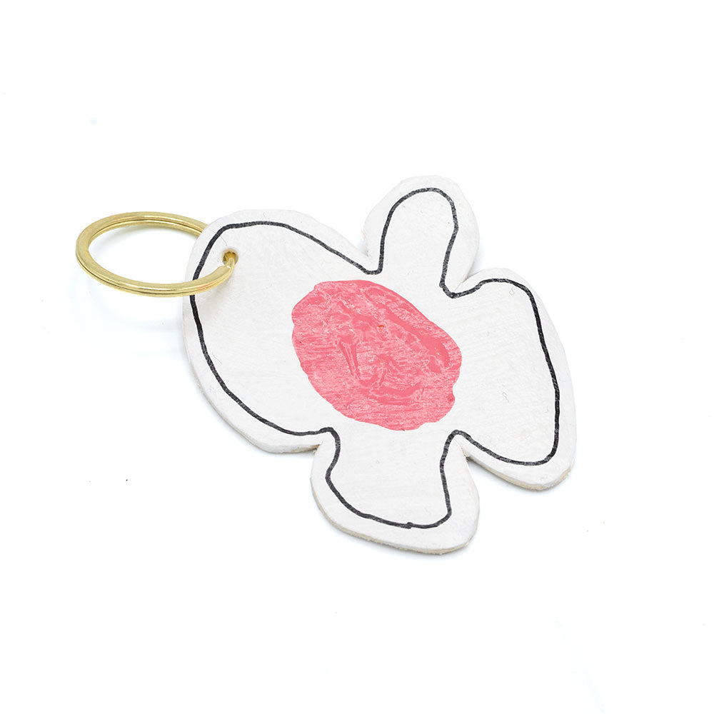 Keyring in the shape of a flower with white petals and a pink centre. Photographed in front of a white background.