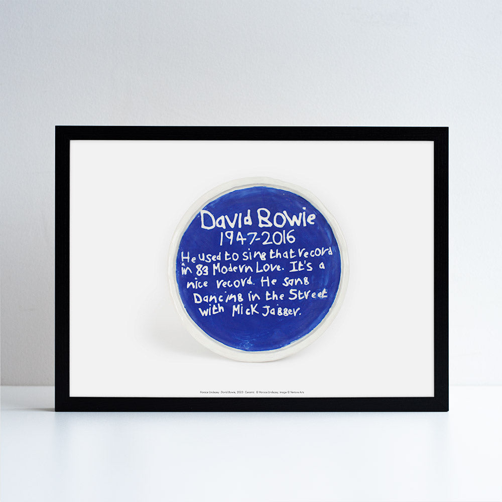 A print in a black frame of a blue plaque sculpture by Horace Lindezey featuring some information about David Bowie