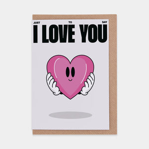 A pink greeting card with the text "JUST SAY I LOVE YOU" in a casual, handwritten font. The lettering is a mix of upper and lowercase letters, and all the words are the same size and color. The background is light pink with a thin white border.