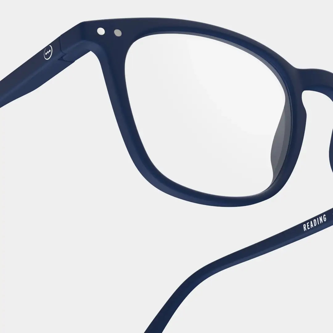 Close up of navy blue reading glasses against a white background.