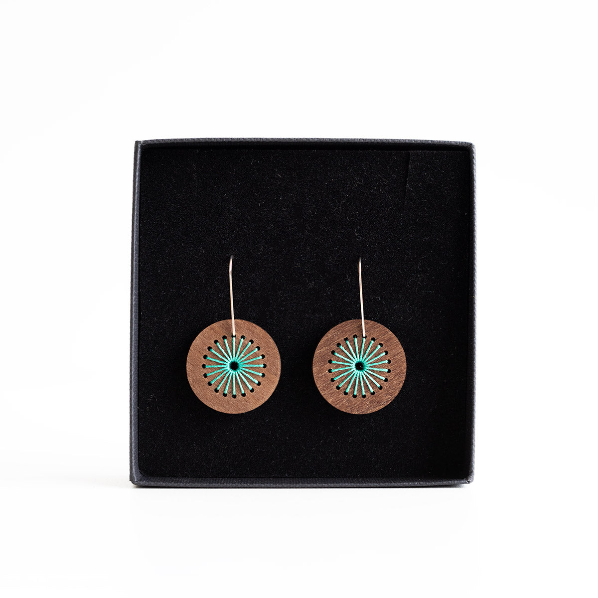 Wooden earrings with turquoise center on a black display card