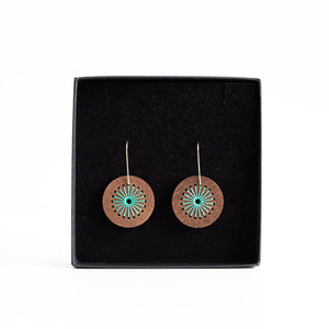 Wooden earrings with turquoise center on a black display card