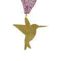 Gold hummingbird ornament with pink and white patterned fabric background