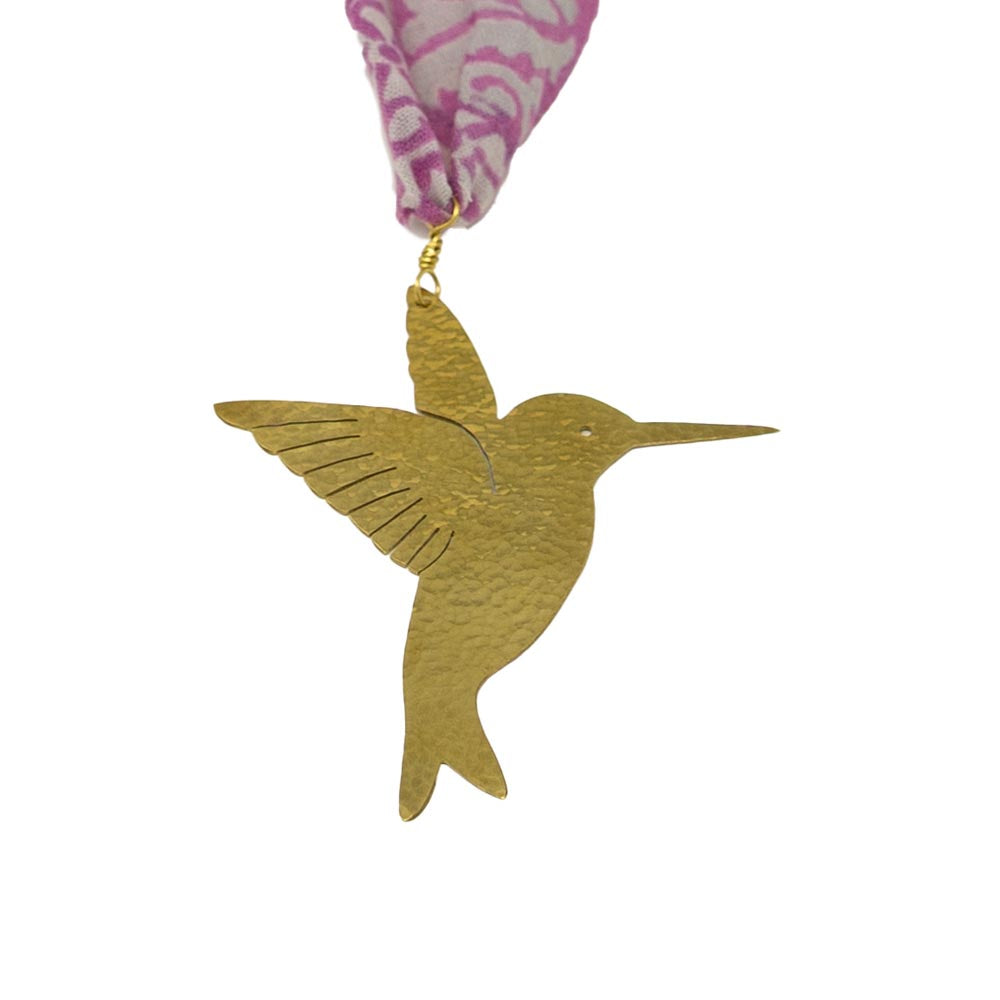 Gold hummingbird ornament with pink and white patterned fabric background