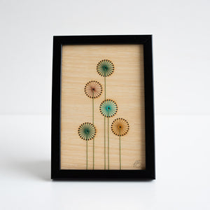 Framed artwork with floral design on a beige wooden background