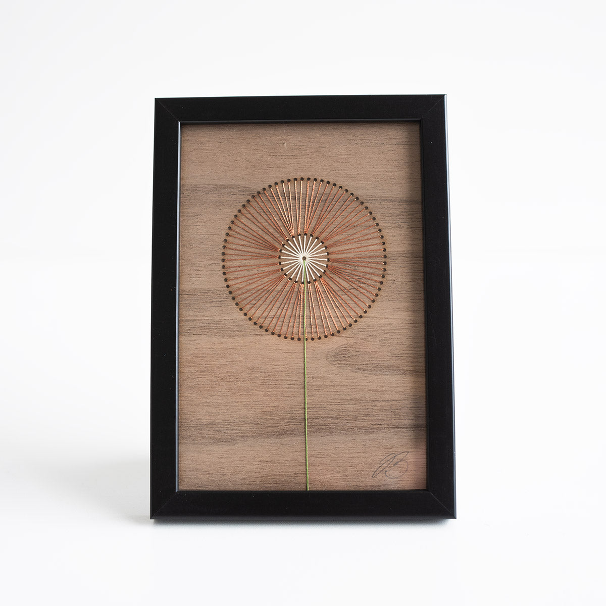 Framed wall art with a circular design on a wooden panel against a white background