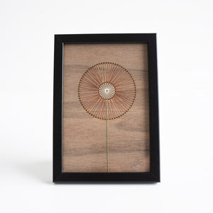 Framed wall art with a circular design on a wooden panel against a white background