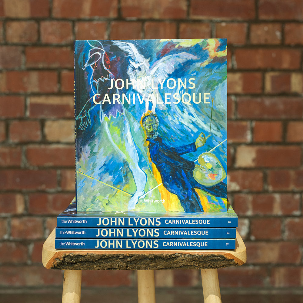 Multiple exhibition catalogues for John Lyons stacked on a stool in front of a brick wall- front cover is a self-portrait.