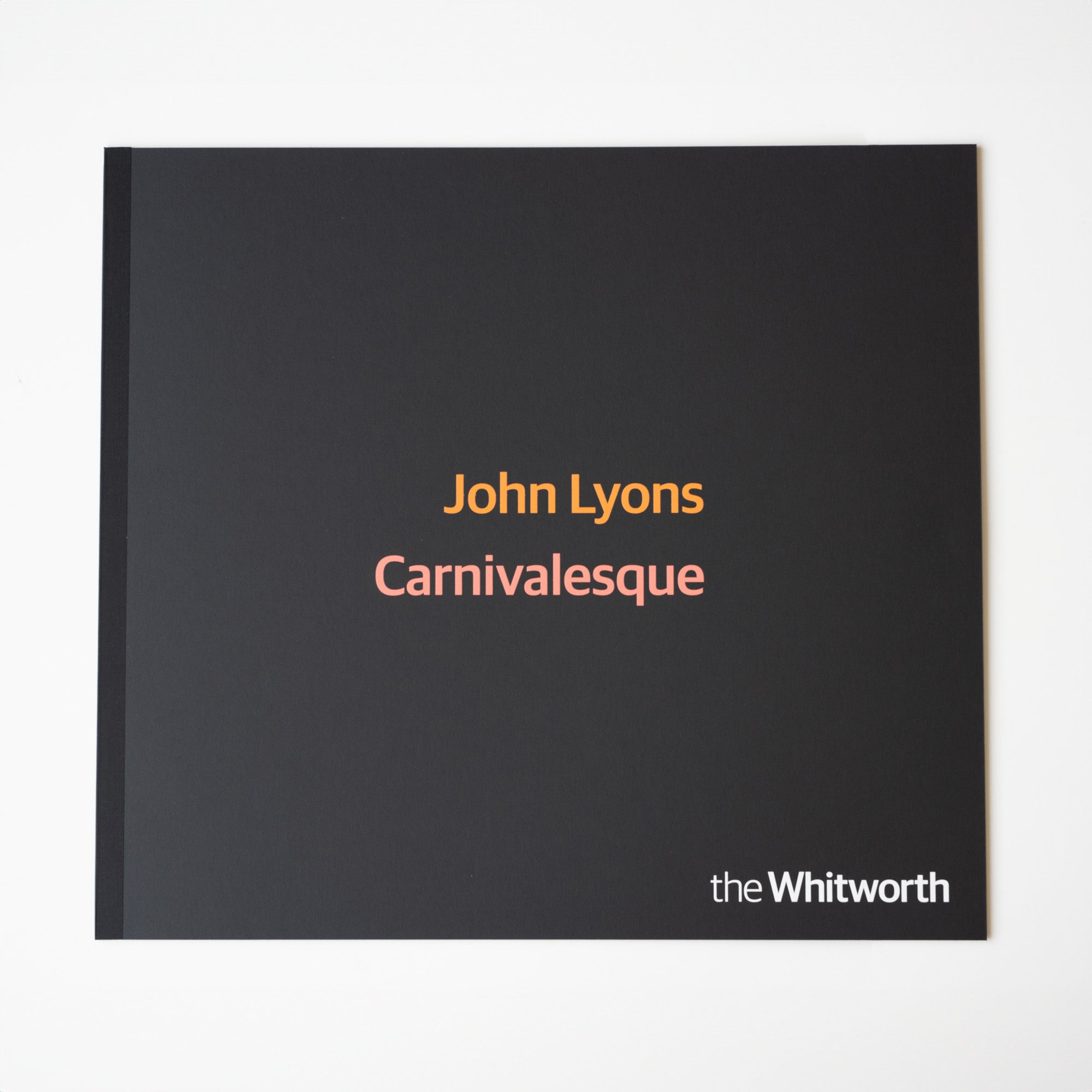 Front cover of black portfolio box with John Lyons carnivalesque title in orange and pink writing.