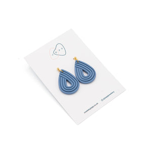 Polymer clay earrings, blue in an upside down tear drop shape, Photographed against Jopp branded backing card.