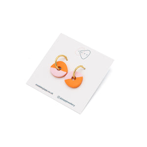 Circular earrings with gold hoop fastening. Top of the circle is orange and the bottom is pink. Photographed against Jopp branded backing card.
