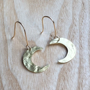 A pair of gold crescent moon earrings with a textured surface.