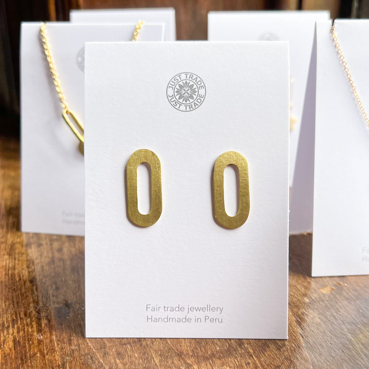 A pair of gold oval earrings with a hollow centre displayed on a card.