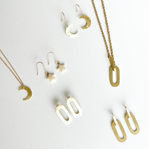 A collection of gold jewellery including crescent moon earrings, a crescent moon necklace, a star-shaped earring pair, a rectangular pendant necklace, and a pair of rectangular earrings.