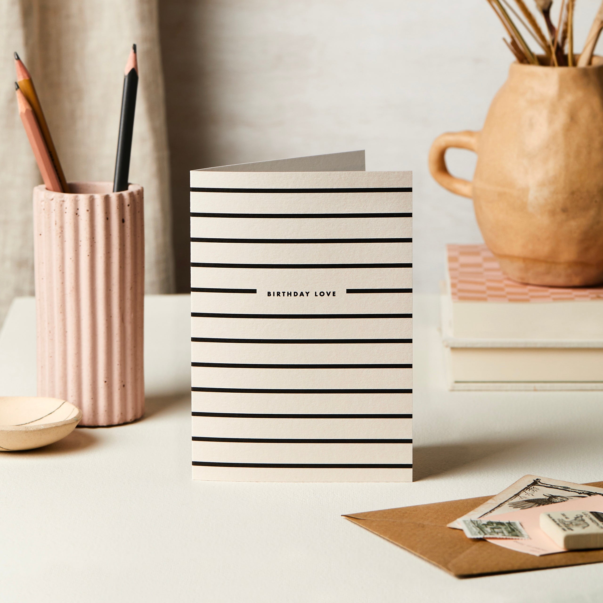 Striped birthday card on a desk with stationery items